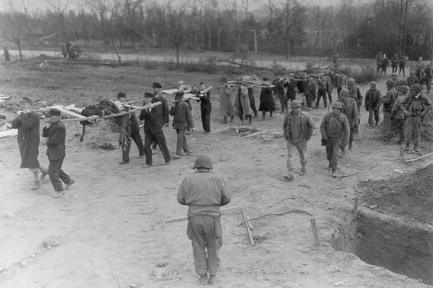 Einwohner Nordhausens tragen unter Aufsicht amerikanischer Soldaten verstorbene Häftlinge des Aussenlagers Boelcke-Kaserne zur Beerdigung.
