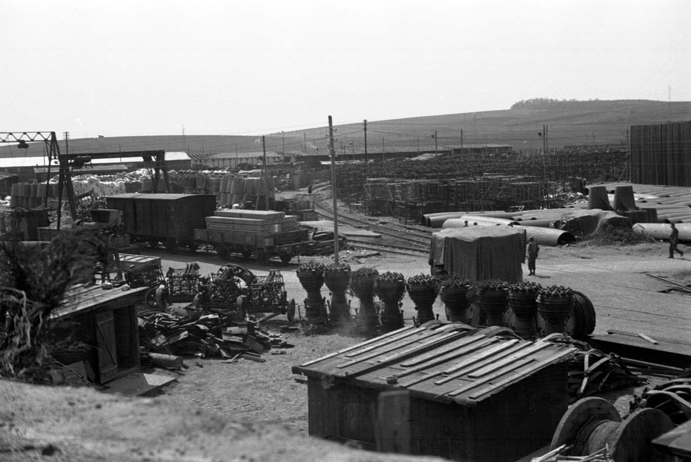 Blick vom Eingang des Fahrstollens B auf den Industriebereich des Lagers Dora, 1945 (nach der Befreiung). In der Bildmitte die Lagerstrasse, im Hintergrund das Bahnhofsgelände, im Vordergrund A4-Triebwerke.