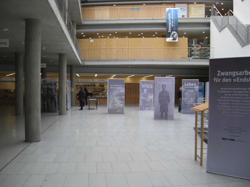 Ein großes Foyer mit zwei Galerien. Im Foyer verteilt stehen die Banner, aus denen die Wanderausstellung besteht.