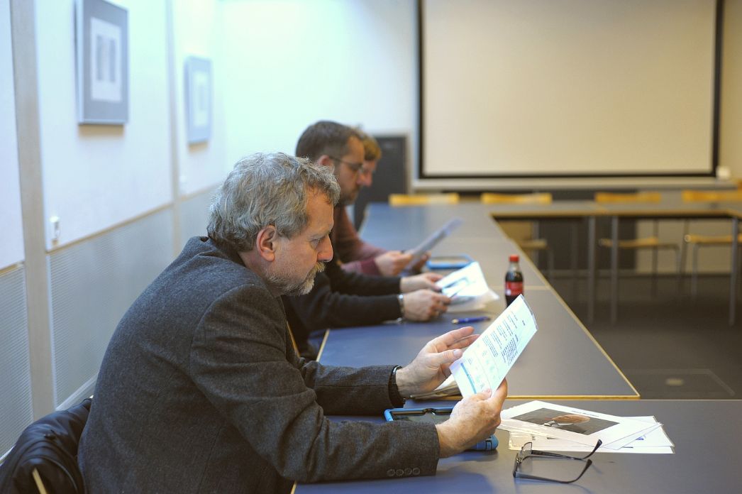 Two seminar participants are sitting at a table in a seminar room, engrossed in some worksheets they are holding in front of them.