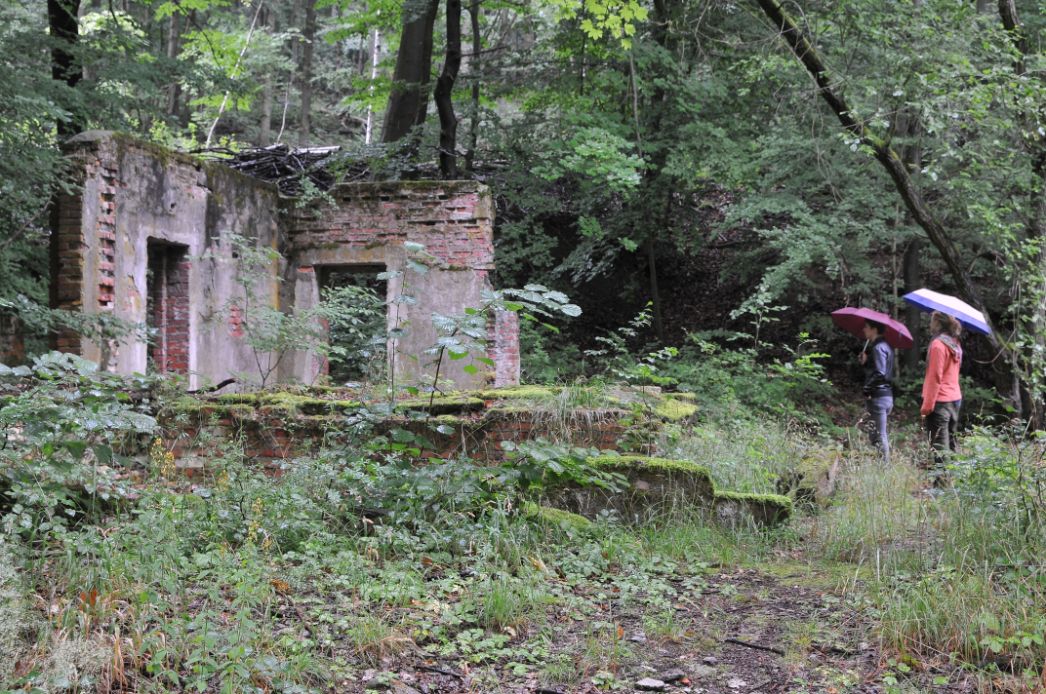 Besucher besichtigen die Ruinen einer ehemaligen Baracke.