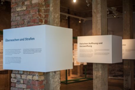 Brick and wood columns support boxes that display informational texts about the exhibition. 