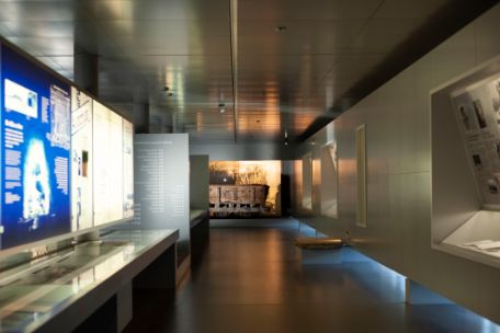 Blick in den Gang der Ausstellung. An den Wänden beleuchtete Tafeln. 