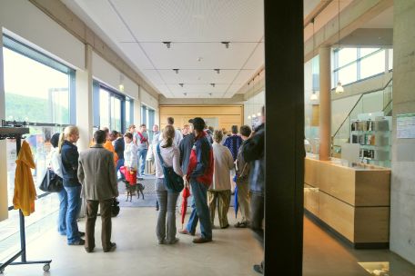 Besucher stehen im Foyer der KZ-Gedenkstätte Mittelbau-Dora und warten auf den Beginn ihrer Führung.