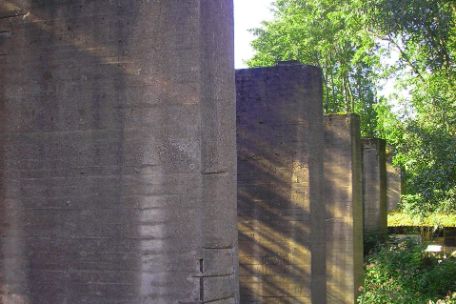 Five massive concrete pillars surrounded by trees.