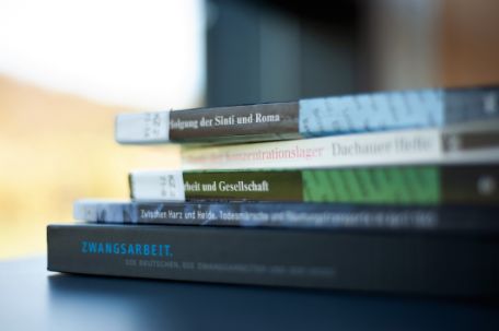 A stack of scientific literature and exhibition catalogs draped on a table in the Mittelbau-Dora Memorial Library.