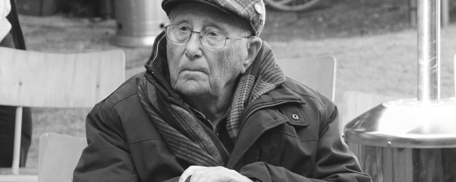 Albrecht Weinberg sitzt auf einem Stuhl und stützt sicht auf einen Gestock.