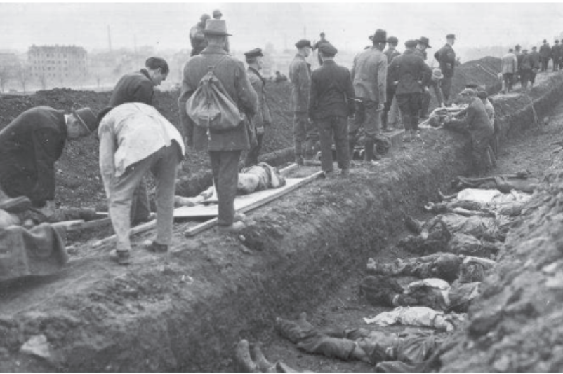 Einwohner Nordhausens beerdigen unter Aufsicht amerikanischer Soldaten die Toten des Außenlagers Boelcke-Kaserne in einem Reihengrab. In dem Grab liegen die toten Körper dicht an dicht.